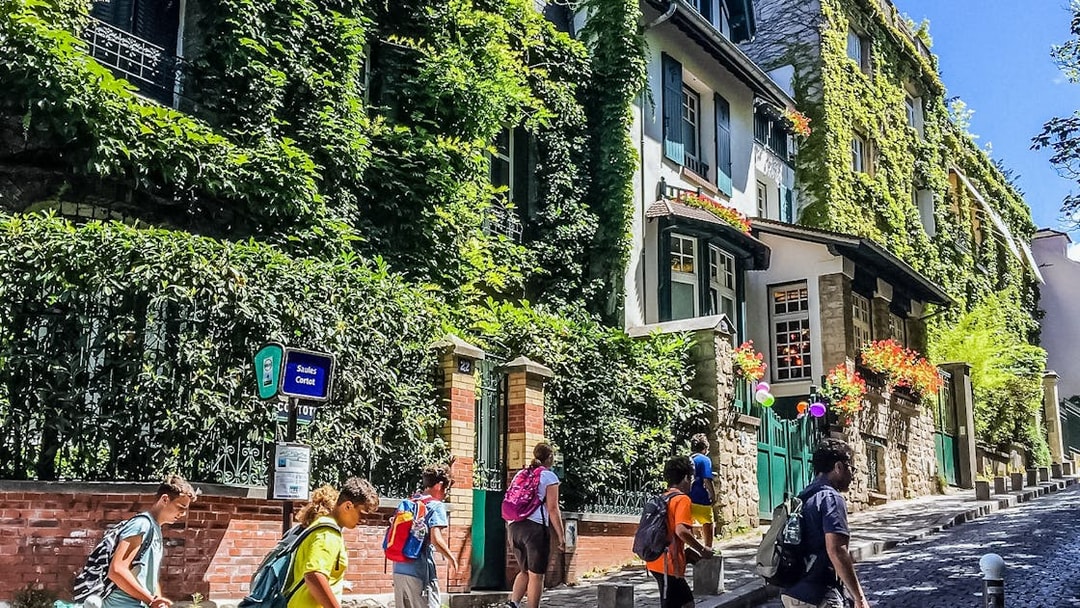 Tourists walking past ivy-covered buildings on Montmartre street, Paris.