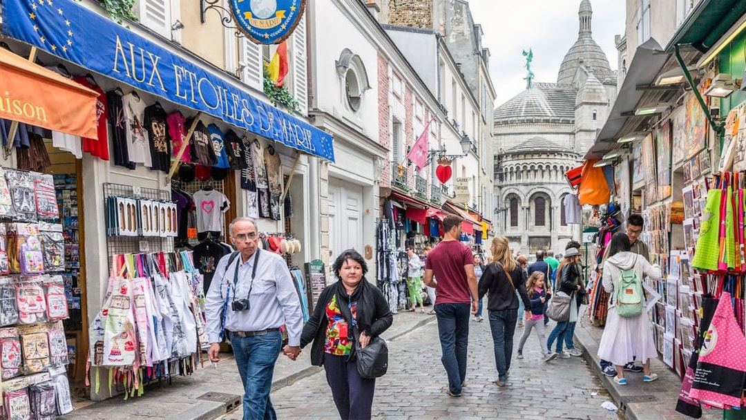 Tourists walking through Montmartre with Sacré-Cœur Basilica in the background, Paris.