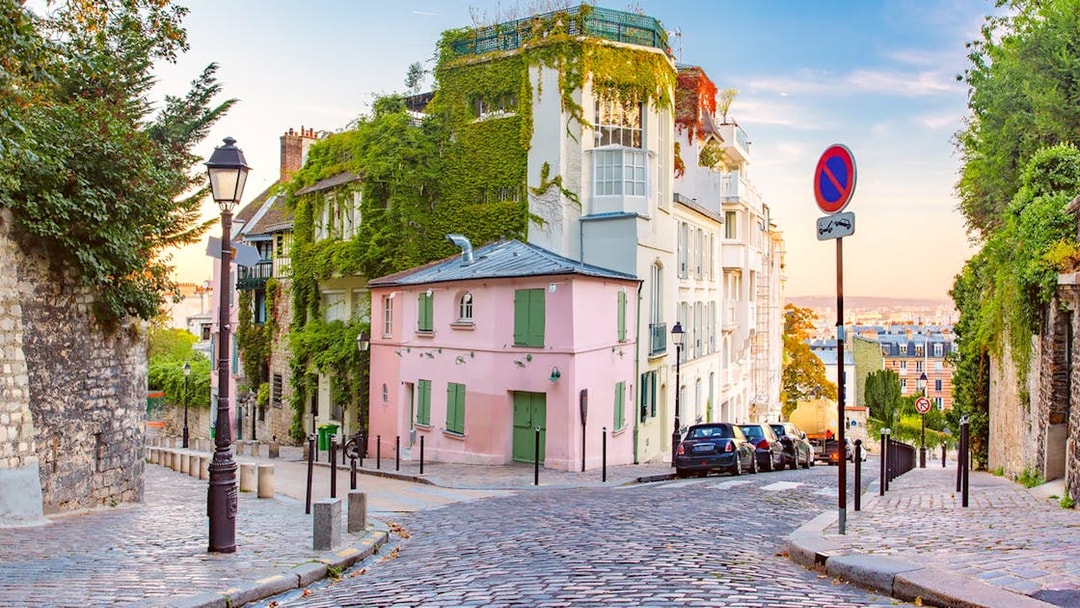 Cobblestone street in Montmartre, Paris, with ivy-covered buildings and a view of the city.