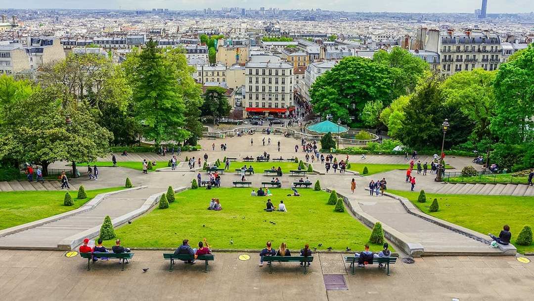 Visitors relaxing on benches in Montmartre with a view of Paris, near Sacré Coeur.