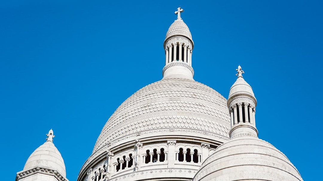 Dome of Sacré-Cœur Basilica against a clear blue sky in Montmartre, Paris.
