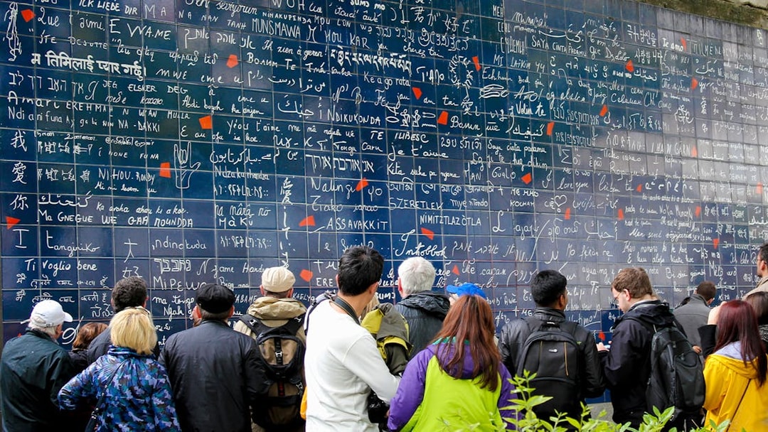 Visitors viewing the Wall of Love in Montmartre, Paris, with "I love you" in multiple languages.