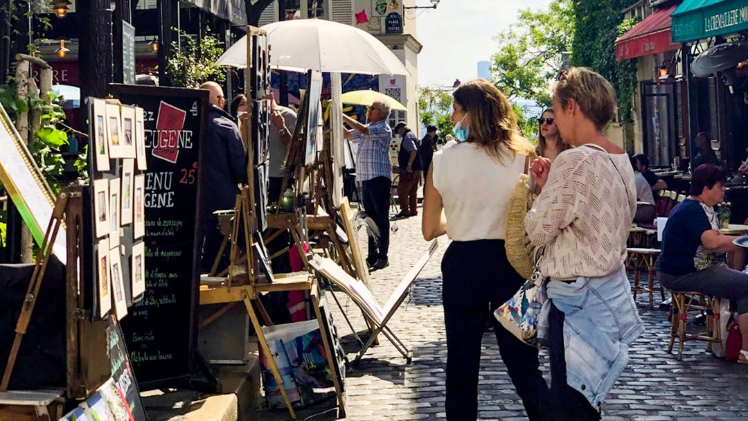 Tourists exploring Montmartre art market on a walking tour in Paris.