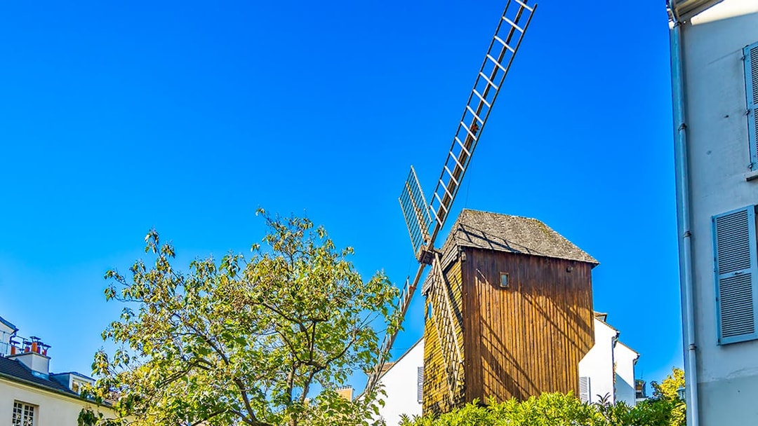 Moulin de la Galette windmill on Montmartre Hill, Paris, surrounded by trees.