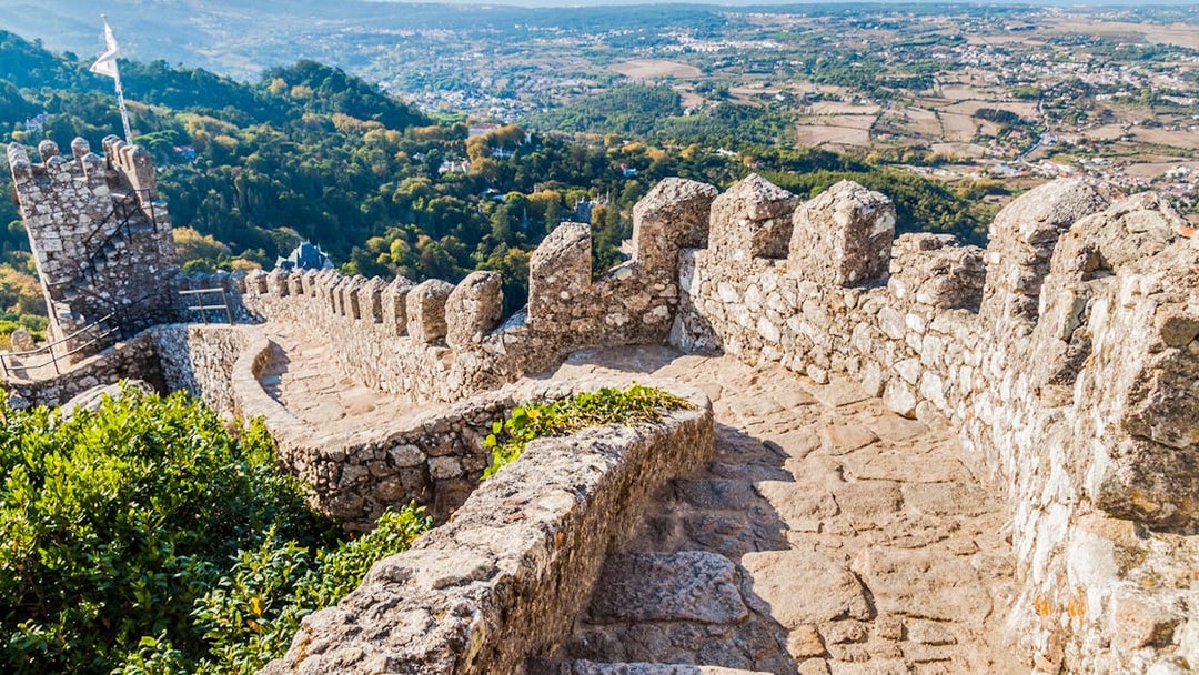 Stone pathway along the walls of Moorish Castle, Sintra, with scenic valley view.