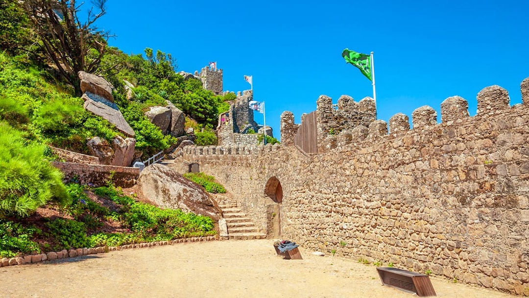 Moorish Castle gates with stone paths and flags in Sintra, Portugal.