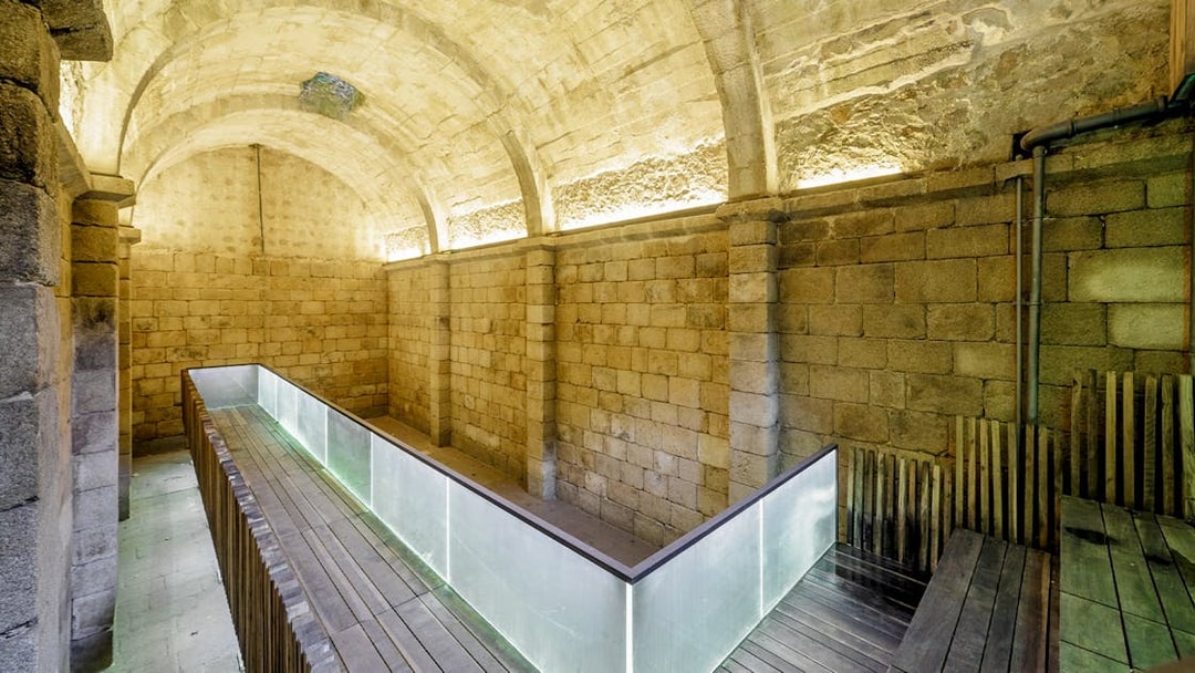 Ancient stone arches and moss-covered walls in Moorish Castle Cistern, Sintra, Portugal.