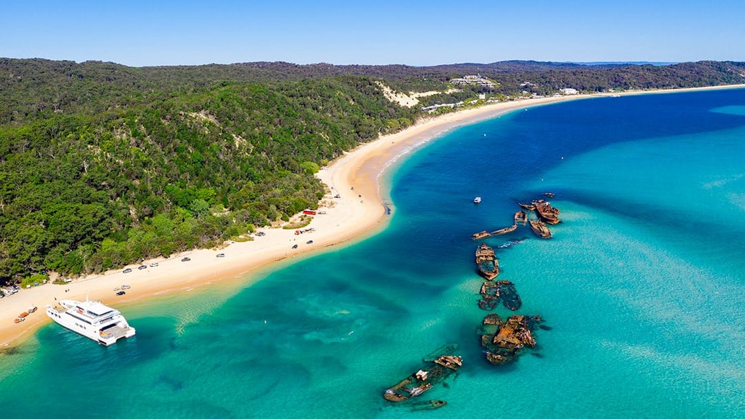 Shipwrecks along the coast of Moreton Island with clear blue waters and sandy beach.