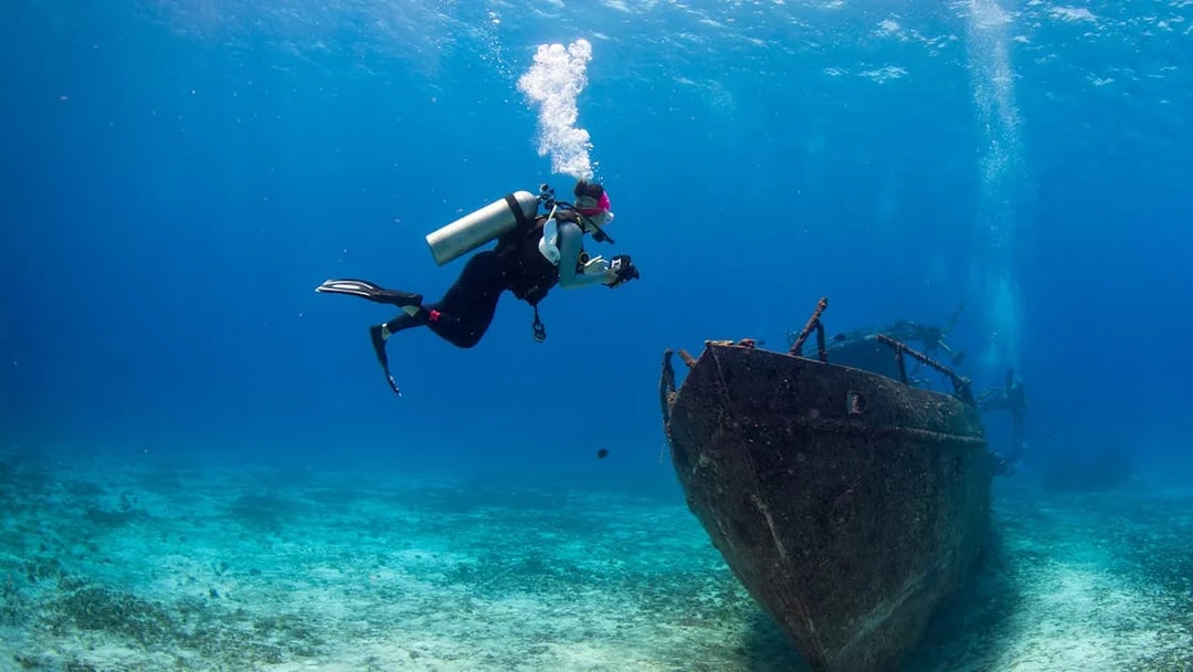 Scuba diver exploring shipwreck at Blue Planet Aquarium.