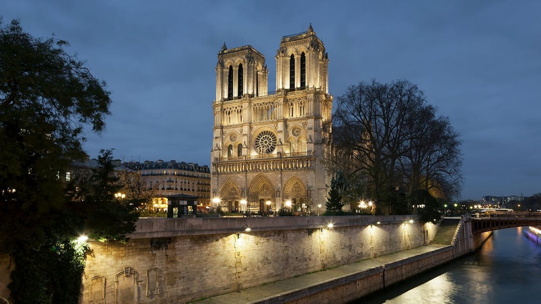 Notre-Dame Cathedral illuminated at night, Paris, near the Seine River.