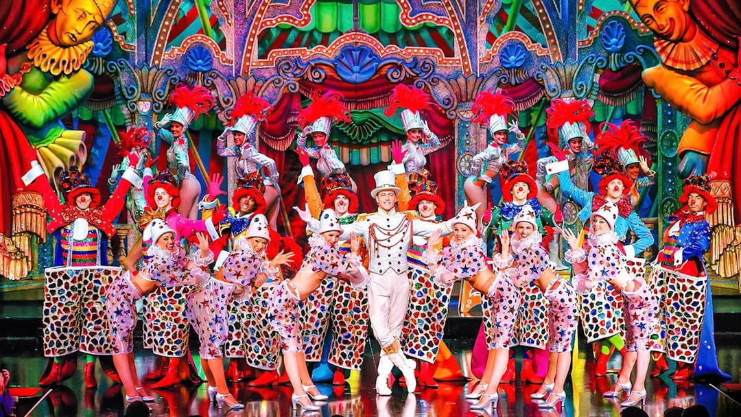 Performers in colorful costumes on stage at the Moulin Rouge show in Paris.