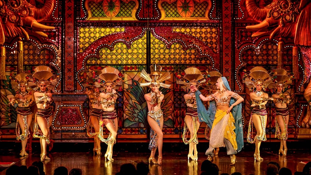 Performers in elaborate costumes on stage at the Moulin Rouge Show in Paris.