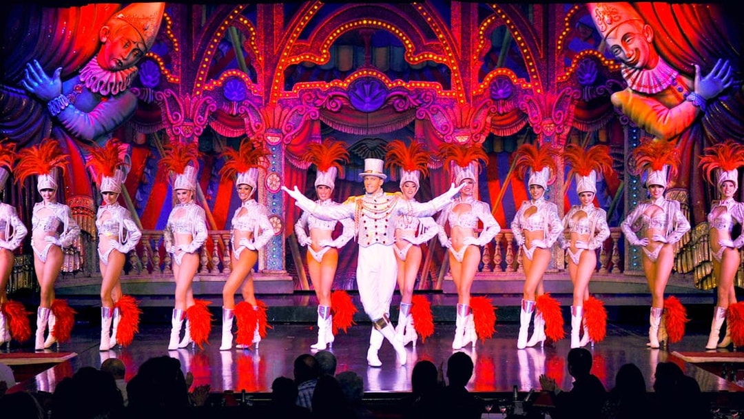 Performers in vibrant costumes on stage at the Moulin Rouge show in Paris.