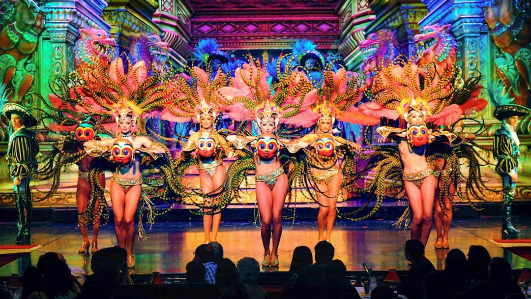 Moulin Rouge Paris dancers performing on stage with vibrant costumes and champagne on table.