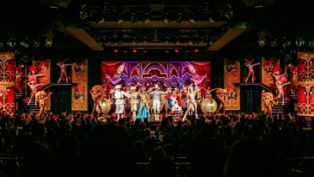 Performers on stage at the Moulin Rouge show in Paris, featuring vibrant costumes and elaborate set design.