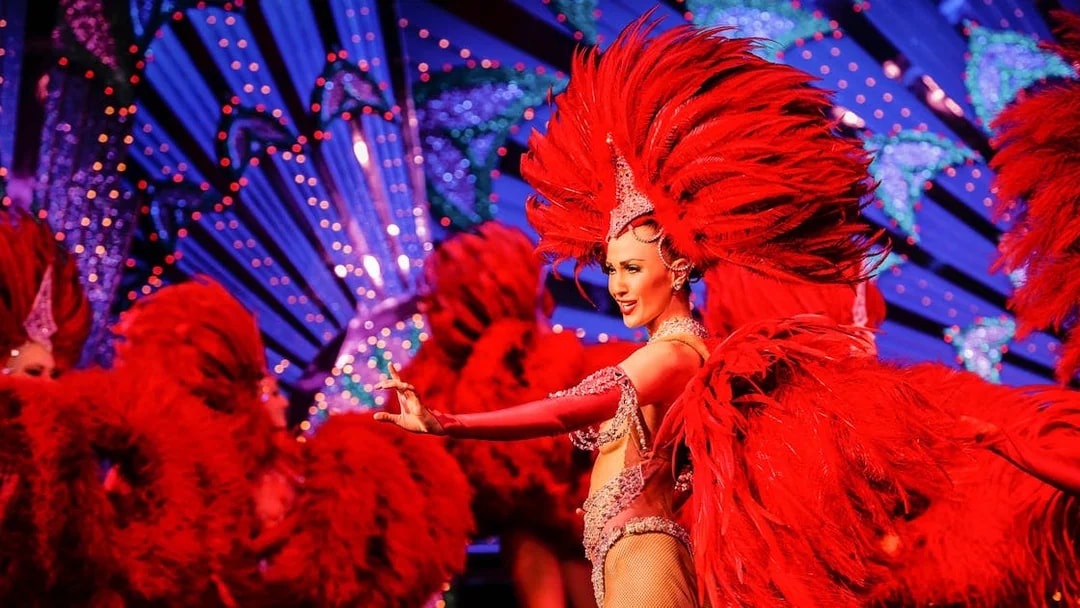 Moulin Rouge dancer in red feather costume performing in Paris, France.