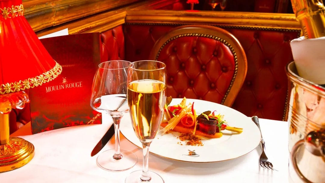 Dinner setting at Moulin Rouge cabaret in Paris with champagne and gourmet dish.