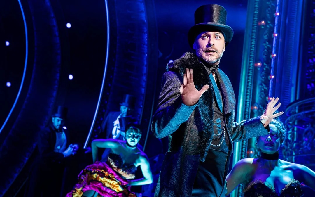 Performer in top hat on stage during Moulin Rouge! The Musical.
