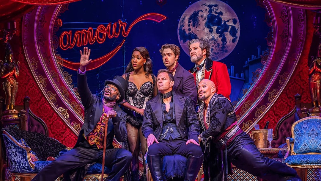 Cast of Moulin Rouge! The Musical on stage with vibrant set design.