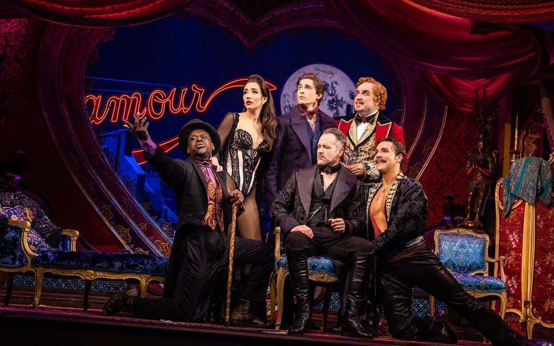 Cast of Moulin Rouge! The Musical on stage with vibrant set design.