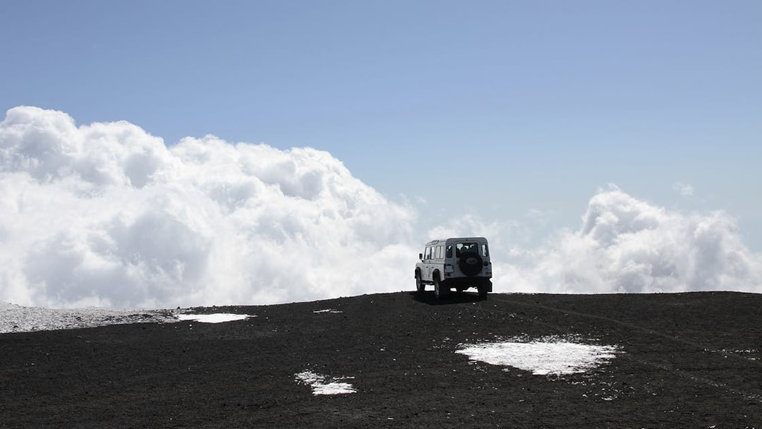 Off-road vehicle on Mount Etna with clouds in the background.