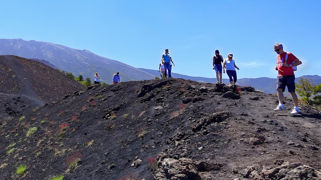 Hikers exploring volcanic terrain on Mount Etna, Sicily.