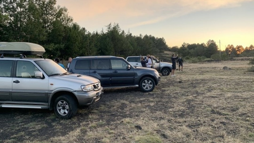 Jeep tour group at Mount Etna with sunset and forest backdrop.