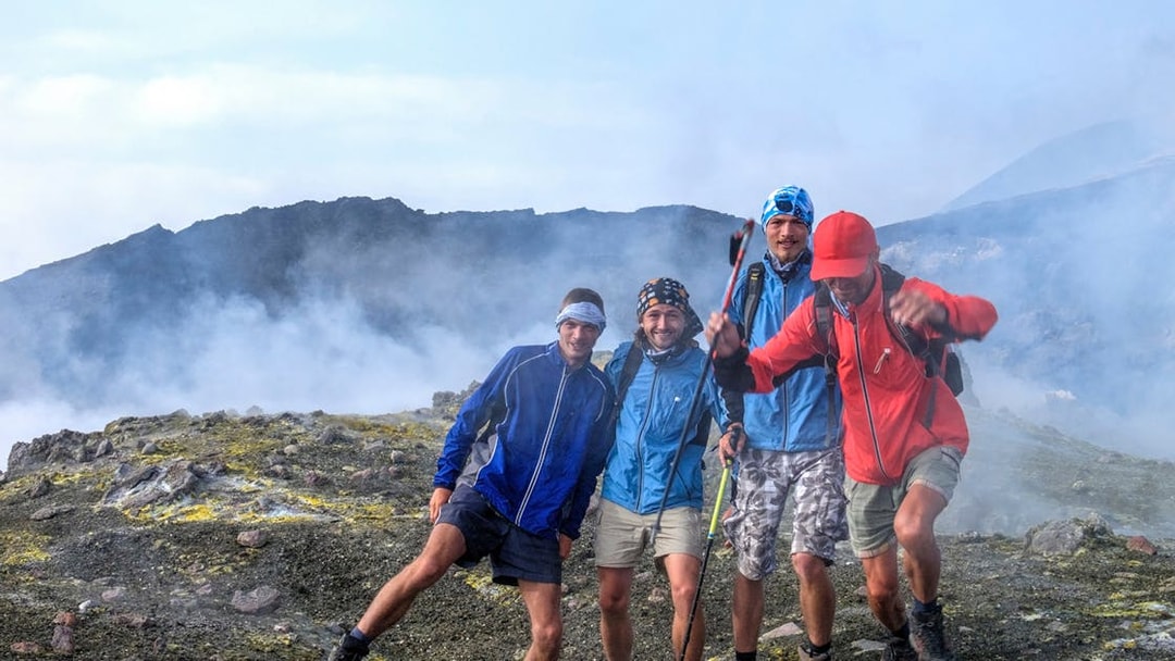 Group hiking on Mount Etna, Catania, with volcanic landscape in the background.