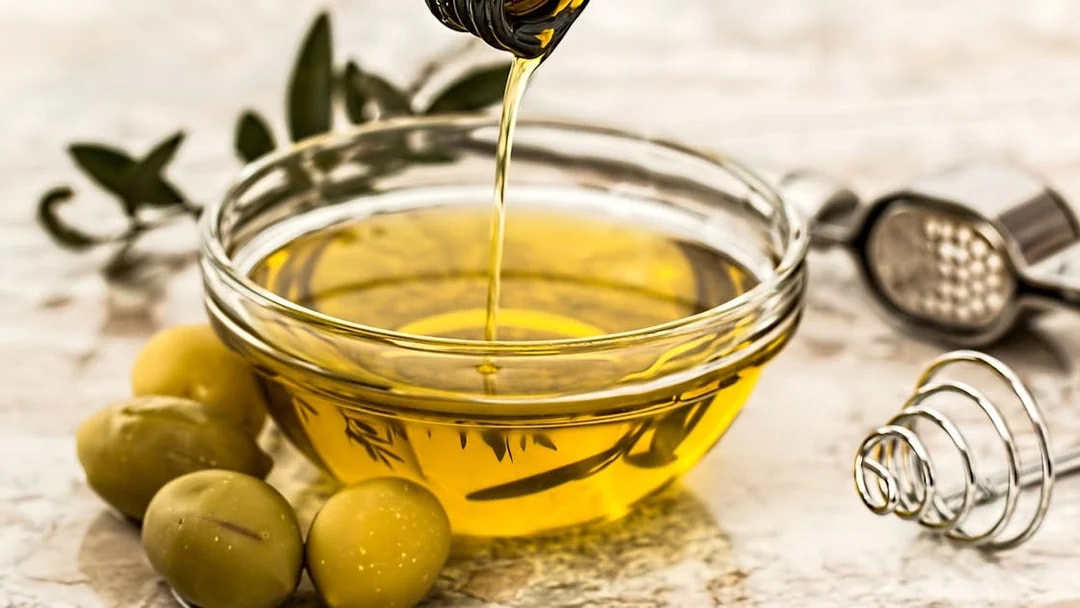 Olive oil being poured into a bowl with olives, part of Mount Etna tour tasting experience.