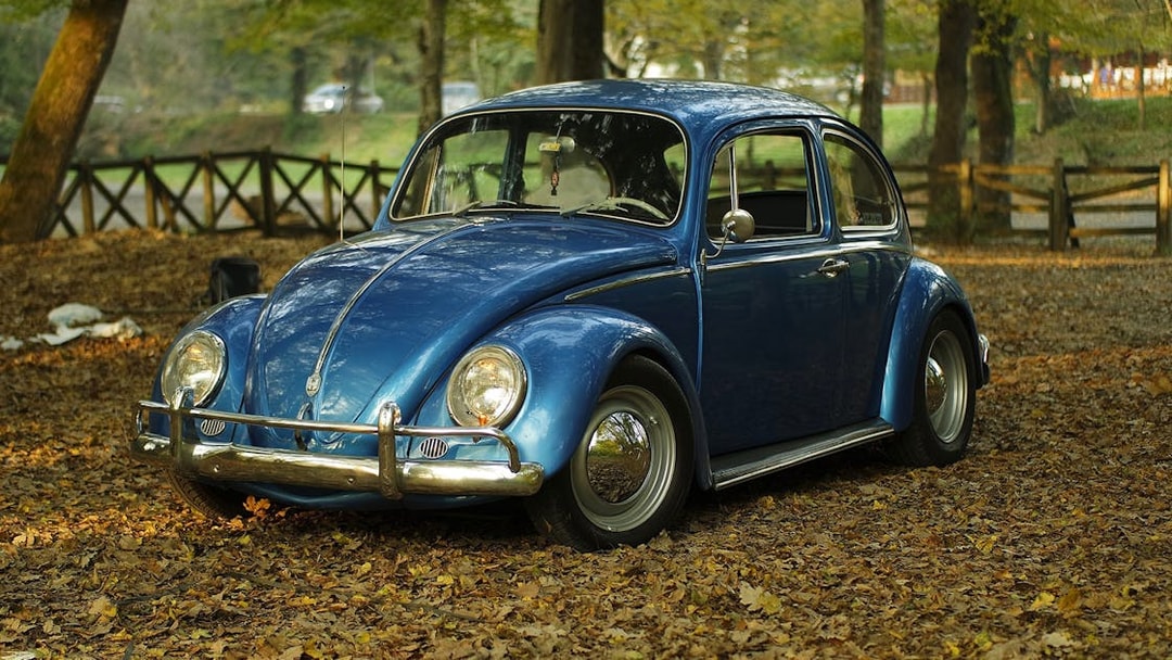 Vintage blue car parked in a forest setting, part of Etna wine tasting tour from Taormina.