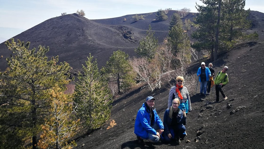 Group hiking on Mount Etna's volcanic terrain, Sicily, during a guided tour.