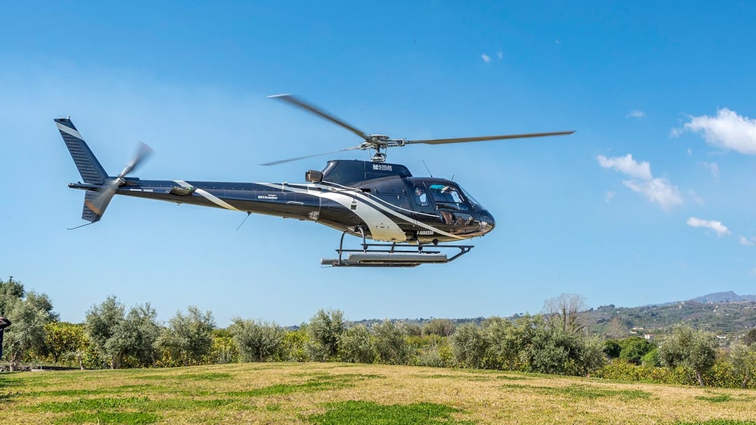 Helicopter flying over green landscape near Etna Volcano, Sicily.