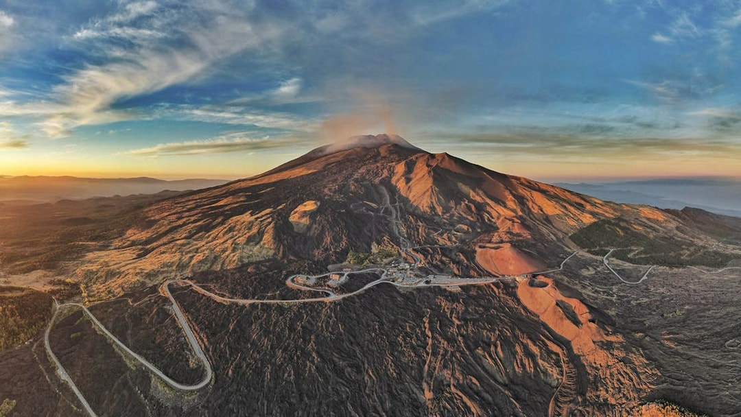 Mount Etna aerial view at sunset with volcanic craters and rugged landscape in Catania, Italy.