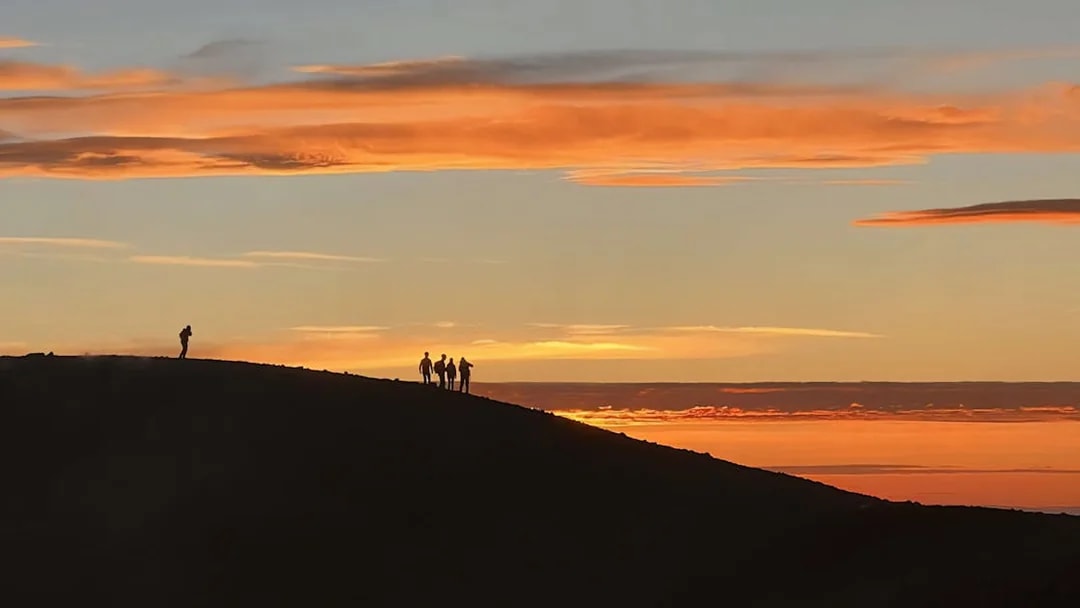 Hikers silhouetted against a sunset at Mount Etna.