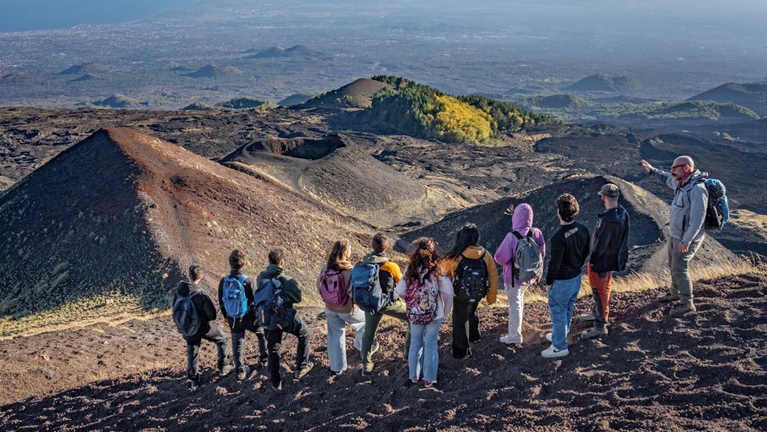 Hikers with guide overlooking volcanic landscape at Mount Etna, Sicily.