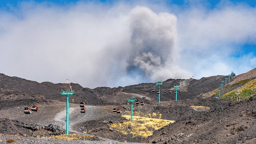Cable car ascending Mount Etna with volcanic crater in background, Sicily.