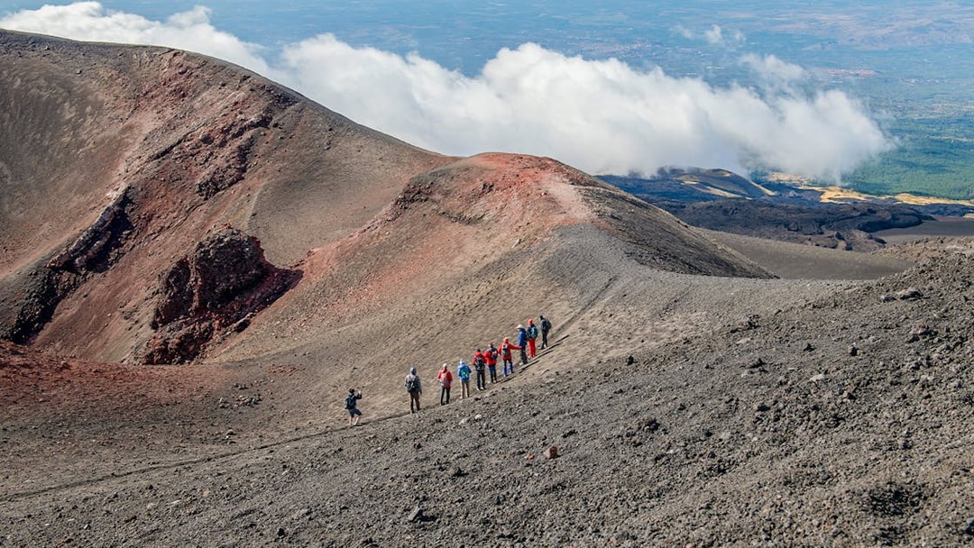 Group hiking along Mount Etna's volcanic ridge during a guided trek.