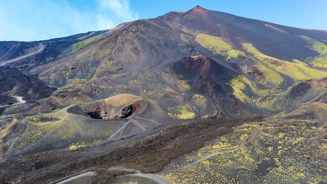 Mount Etna's volcanic landscape with craters and trails, viewed from a helicopter tour.