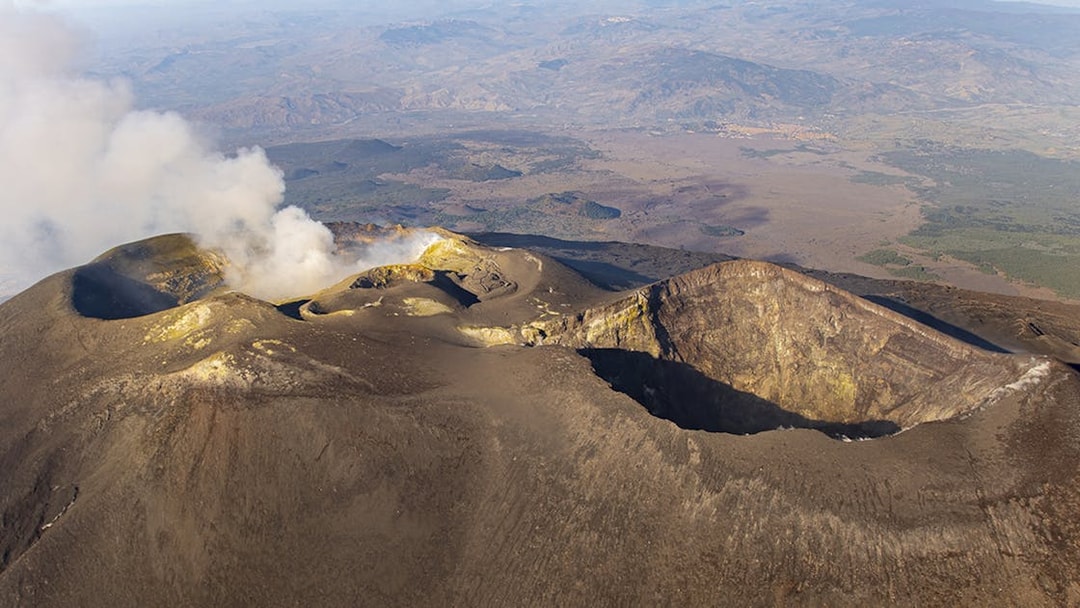 Aerial view of Mount Etna's craters with smoke rising, Sicily, Italy.