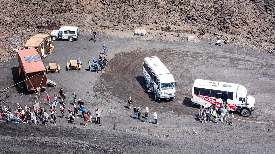 Tourists disembarking from 4x4 vehicles at Mount Etna's volcanic landscape.
