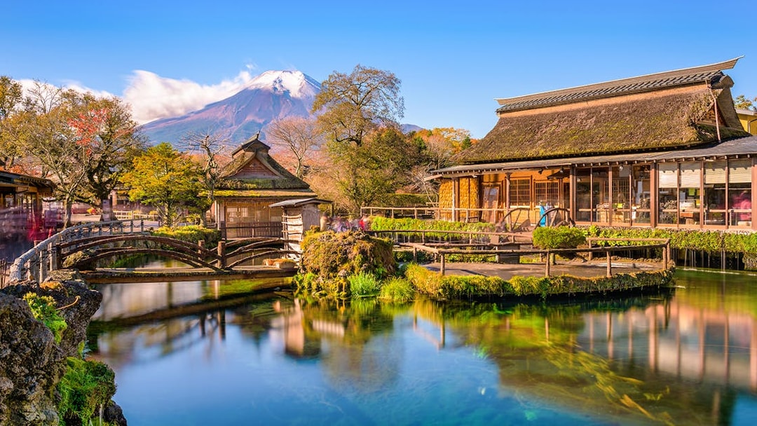 Traditional buildings and pond at Oshino Hakkai Village, Japan, with Mount Fuji in the background.