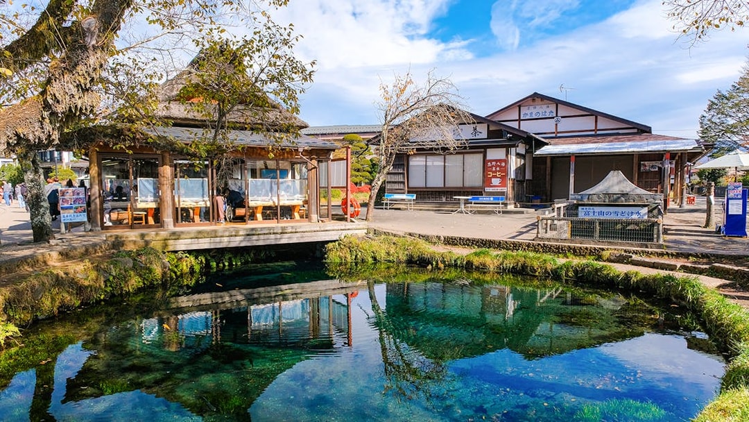 Owaike Pond in Oshino Hakkai Village, Japan, with traditional buildings and clear water.