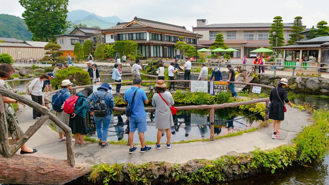 Visitors exploring ponds and traditional buildings at Oshino Hakkai Village, Japan.
