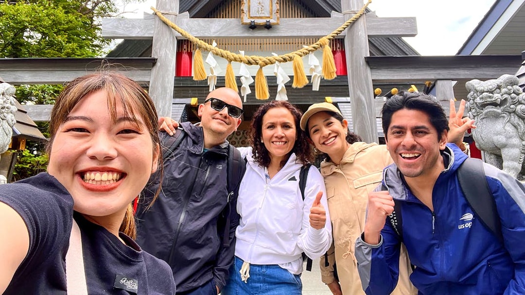 Group of tourists smiling in front of a shrine on the Fantastic Fuji & Hakone 1-Day Bus Tour.