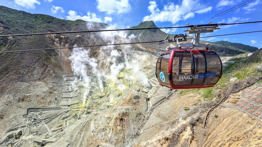 Hakone Ropeway cable car over Owakudani volcanic valley with steam vents, Japan.