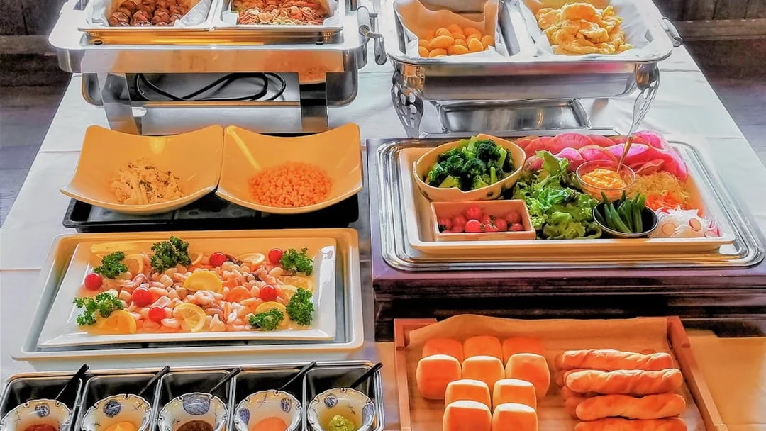Buffet spread with assorted dishes on Mount Fuji Day Tour, featuring fresh vegetables and bread rolls.