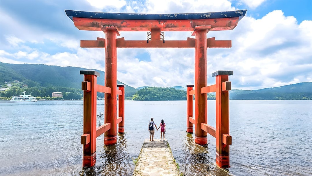 Couple standing at Hakone Torii Gate overlooking Lake Ashi, Japan.