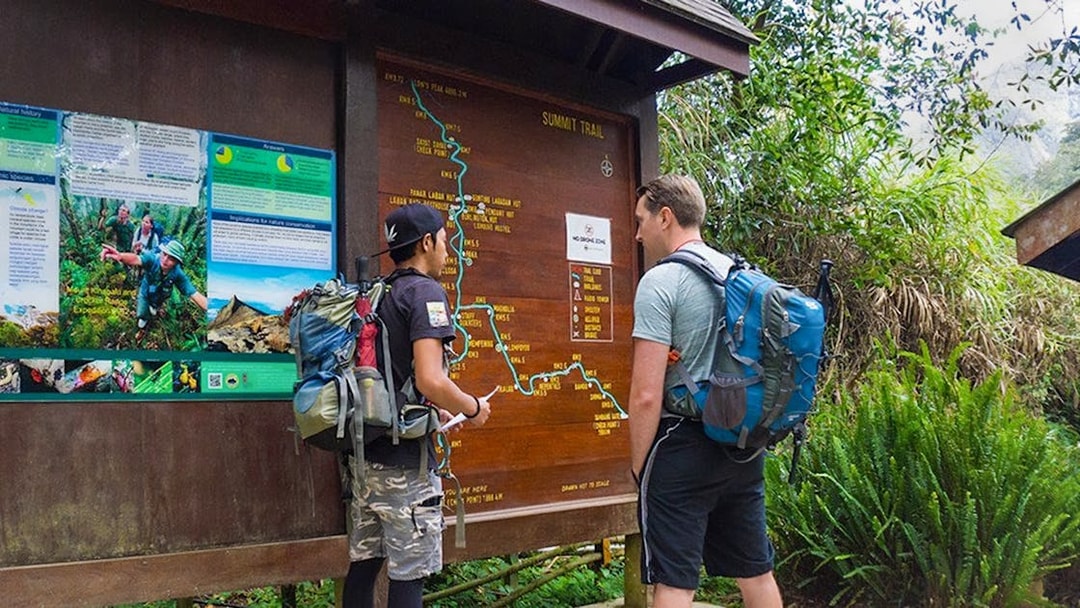 Hikers examining trail map at Mount Kinabalu Summit Tour starting point.