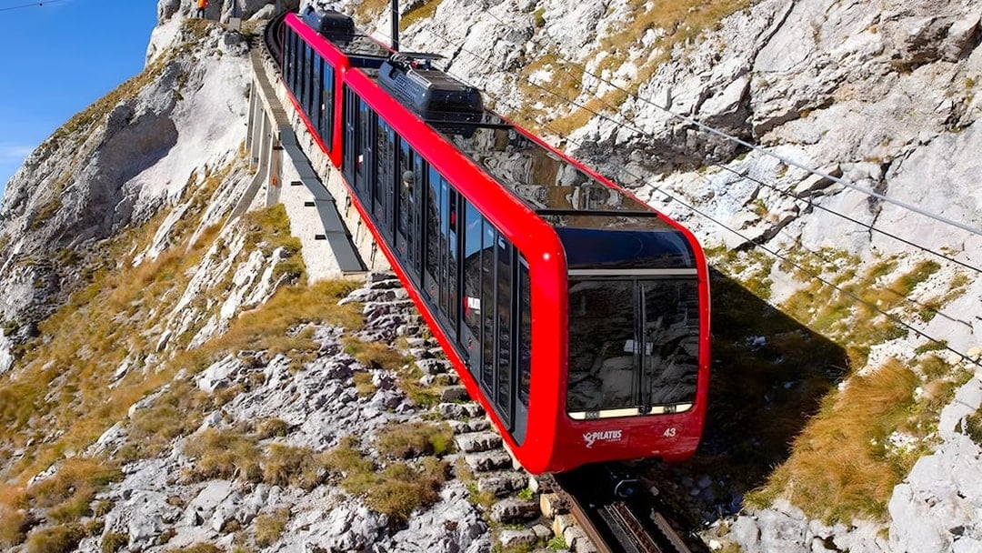 Rack railroad train ascending Pilatus Kulm from Alpnachstad through rocky terrain.