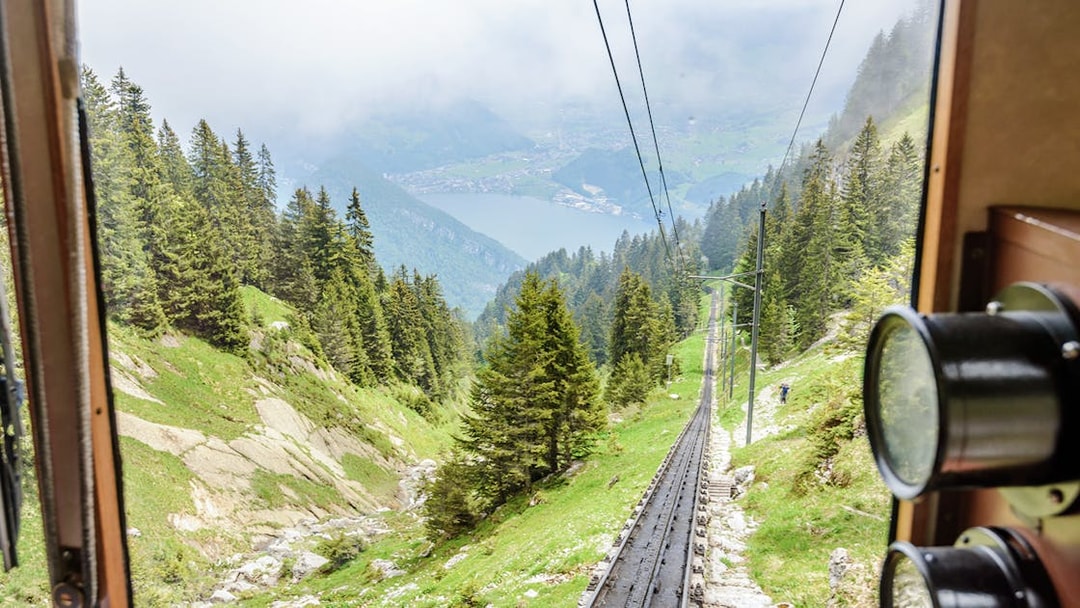 Mount Pilatus cogwheel train ascending through Swiss Alps with lake view.